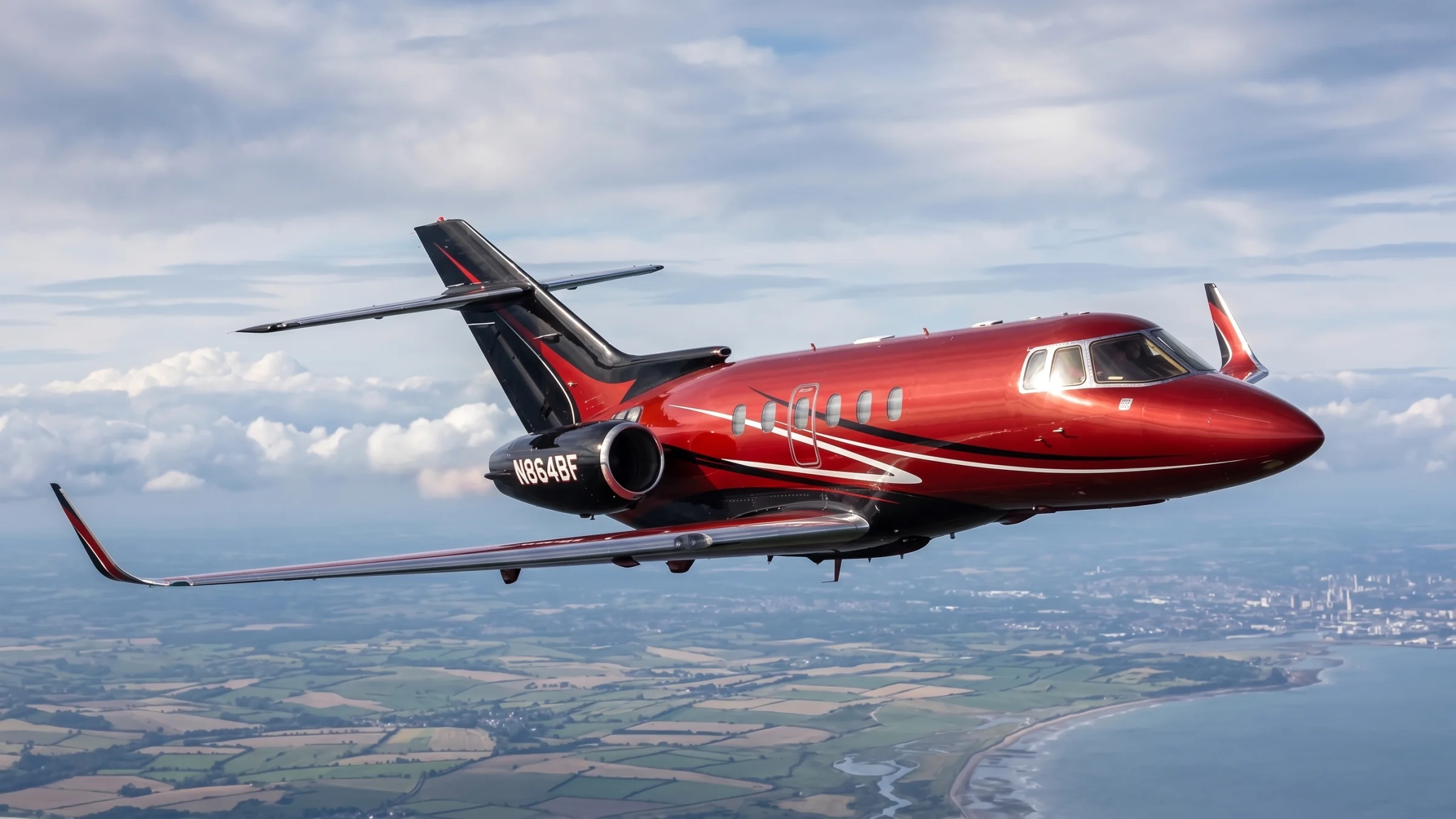 Burgundy private jet flying above a landscape
