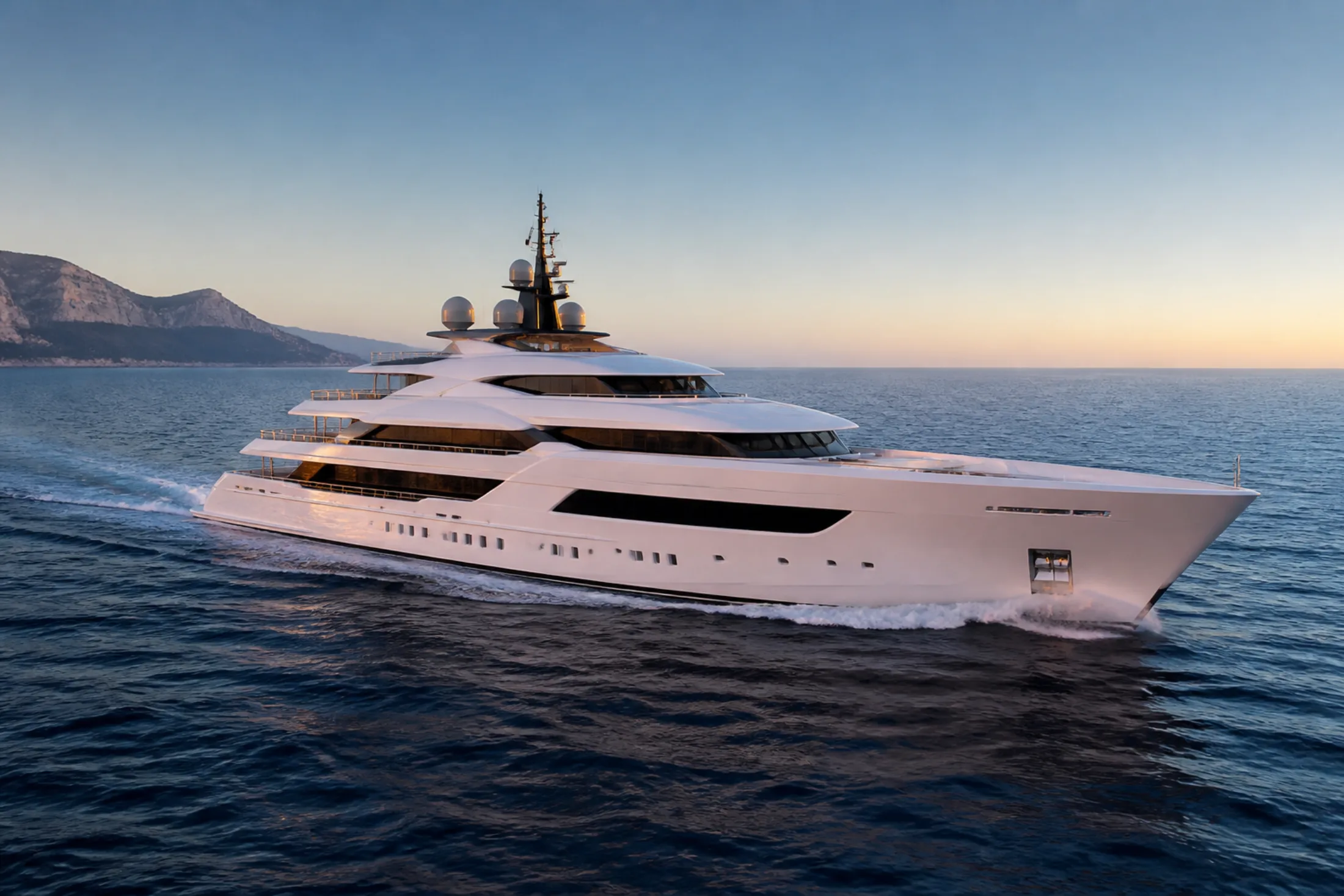 Pearl-white superyacht moving through the Mediterranean at dawn